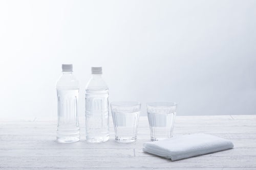 ミネラルウォーターのボトルとグラスの水の写真