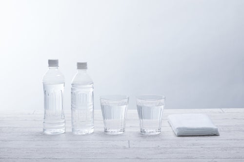 ペットボトル2本とグラスの水の写真