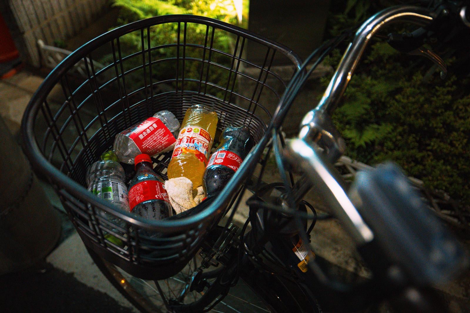 「駐輪している自転車のかごにペットボトルのポイ捨て」の写真