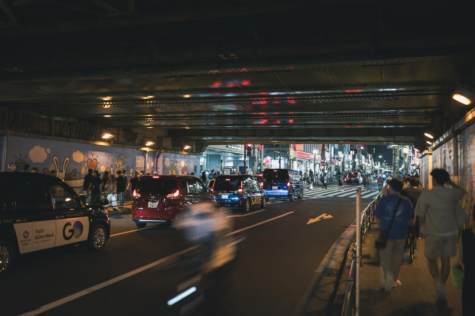 「新大久保駅高架下の歩行者と信号待ちの車（夜間）」の写真