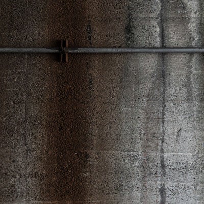 細い管とコンクリート壁のテクスチャーの写真