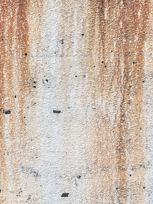 モルタル壁と流れ落ちる錆の写真