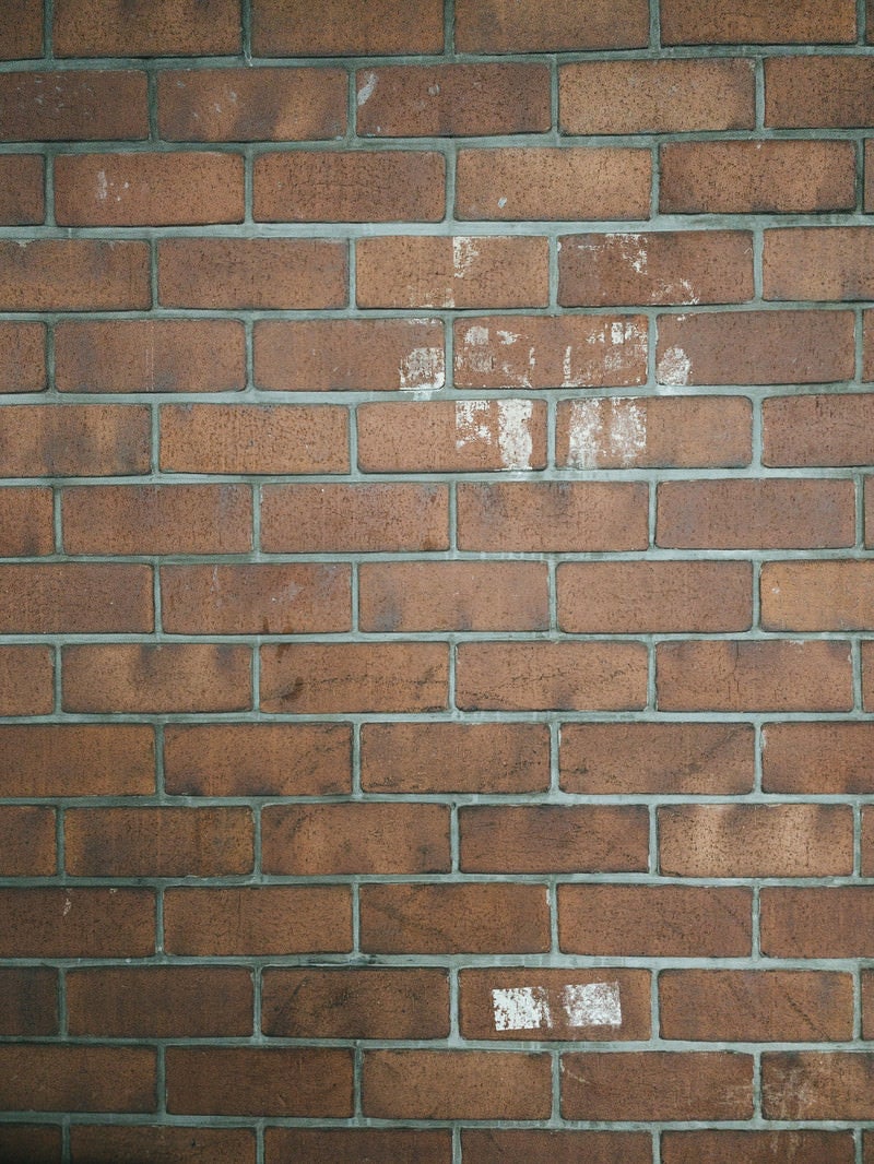 「白いテープ跡が残ったレンガ壁（テクスチャ）」の写真