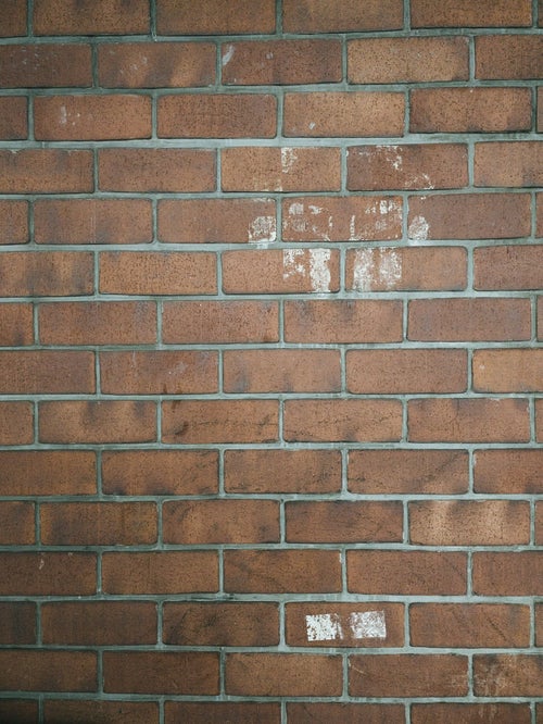 白いテープ跡が残ったレンガ壁（テクスチャ）の写真