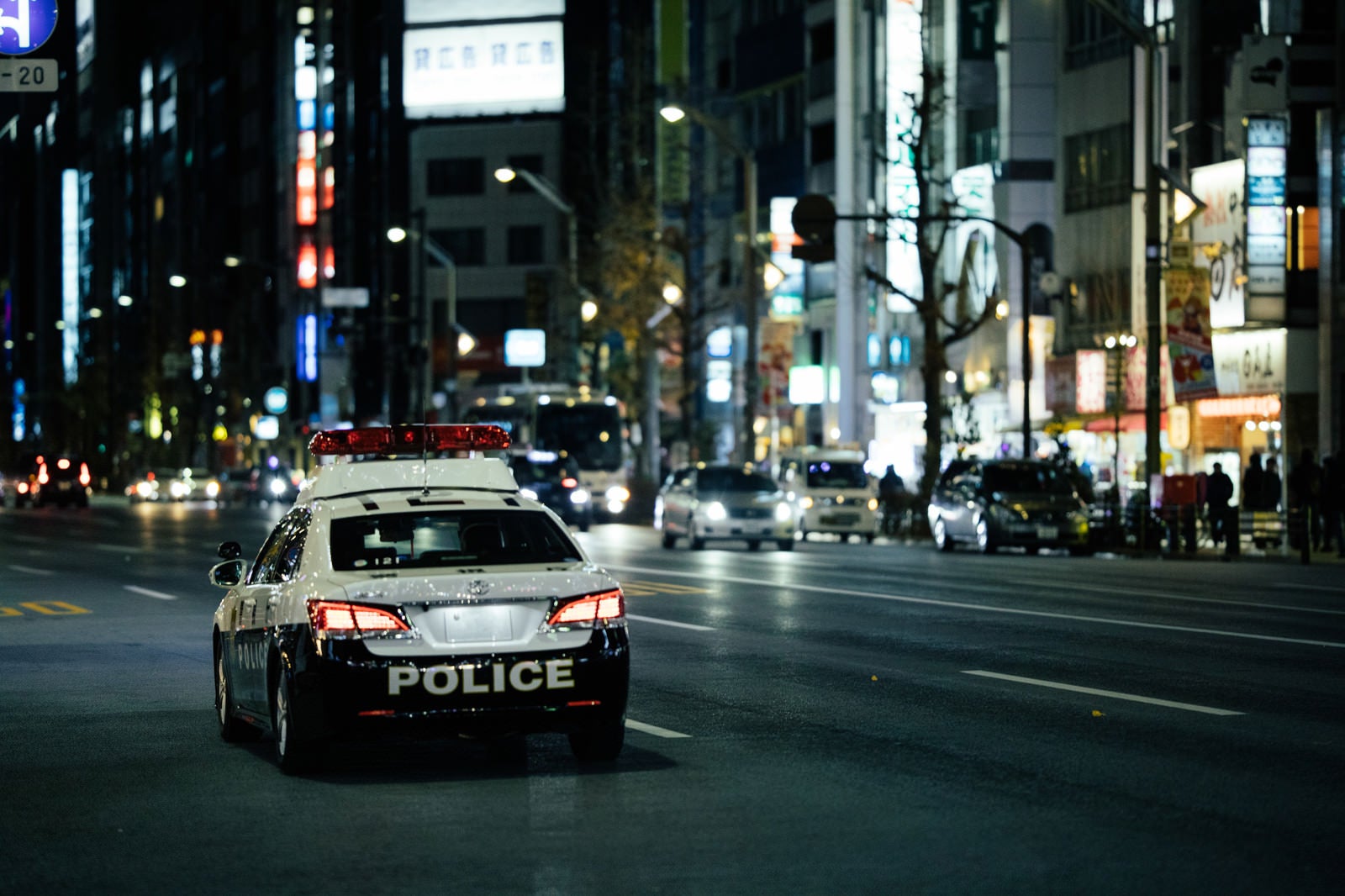 「夜の繁華街を巡回するパトカー」の写真