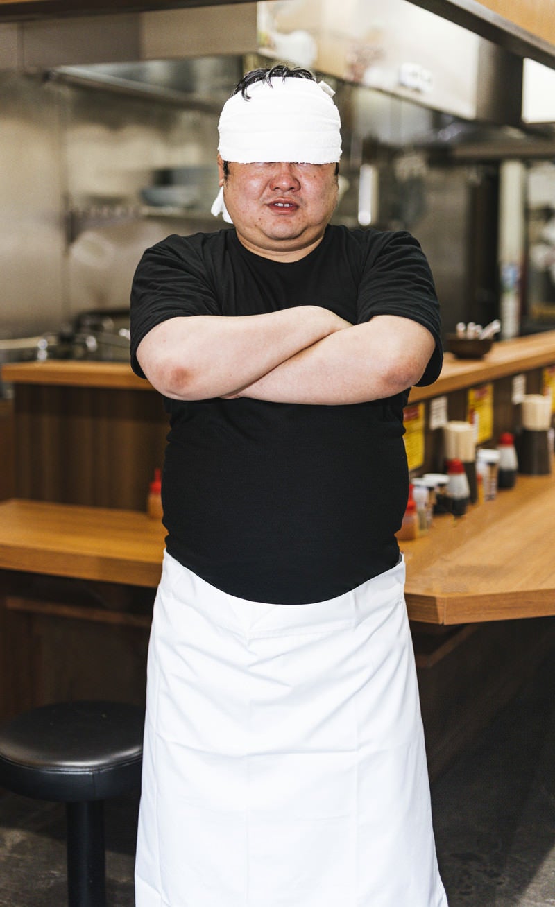 「インタビューに応えるつけ麺屋店主」の写真［モデル：段田隼人］