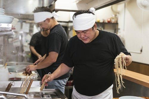 麺を片手にテボをチェックするラーメン屋の店主の写真