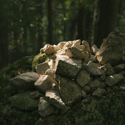 苔むした岩の上に丁寧に積み上げられた光が差す積石の素材