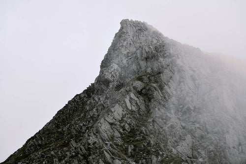 ガスから顔を出す奥穂高岳の岩肌の写真