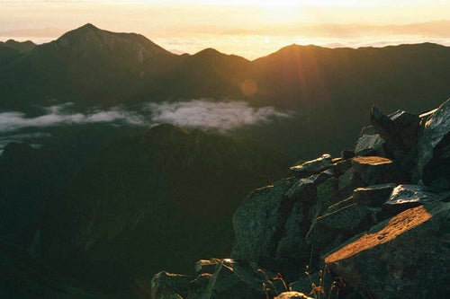 差し込む朝日と常念岳のシルエットの写真