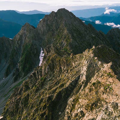 朝日に染まる北アルプスの前穂高岳と奥穂高岳の険しい峰々の写真