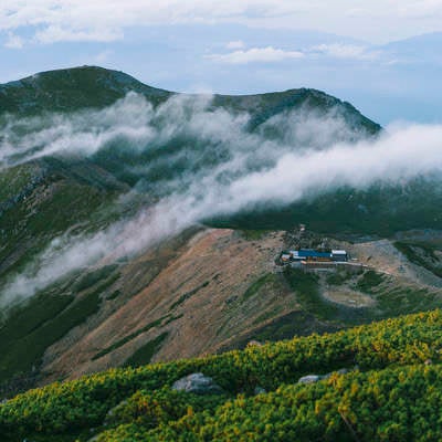 流れる雲に包まれる五ノ池小屋と継子岳の写真