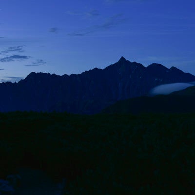 夜明けにシルエットが浮かび上がる槍ヶ岳（鷲羽岳）の写真
