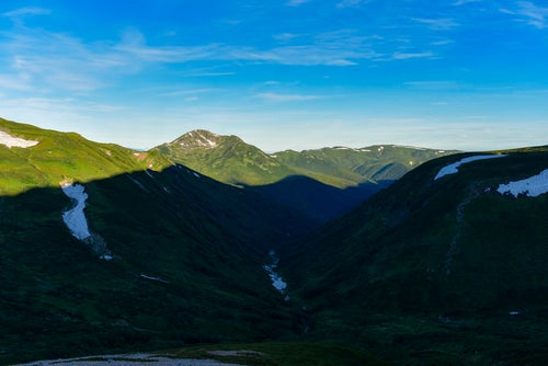 朝日を受ける黒部五郎岳と山々の影（鷲羽岳）の写真
