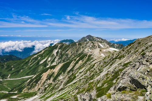 立山の登山道の奥に続く剱岳の写真