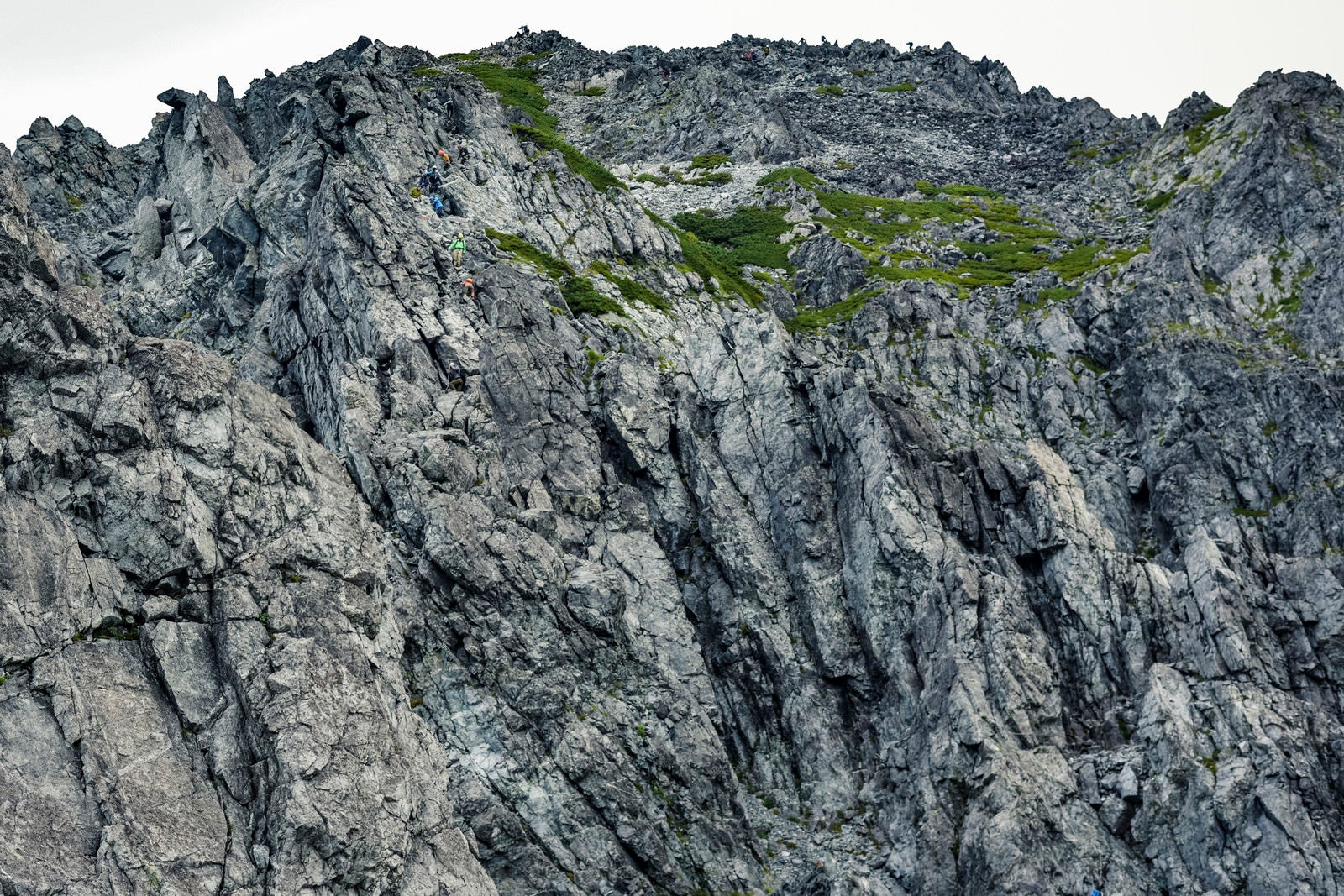 「岩の殿堂たる剱岳を登る登山者」の写真
