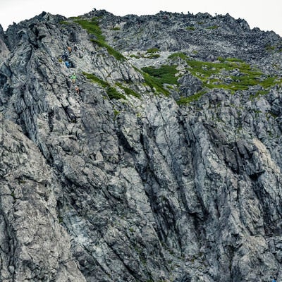 岩の殿堂たる剱岳を登る登山者の写真