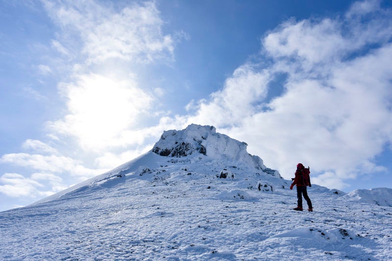安達太良山山頂を眺める赤い登山者の写真