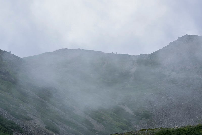 雲に包まれる稜線を歩く登山者たち（仙丈ヶ岳）の写真