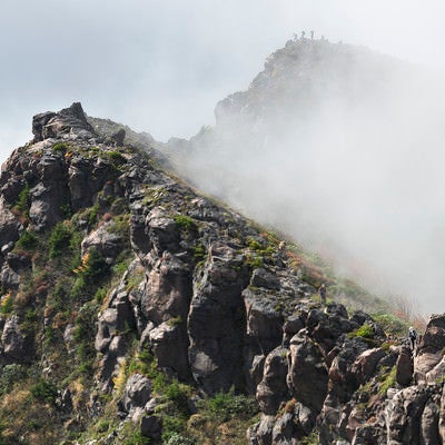 ガスに包まれた蛇骨山の稜線を歩く登山者（浅間山）の写真