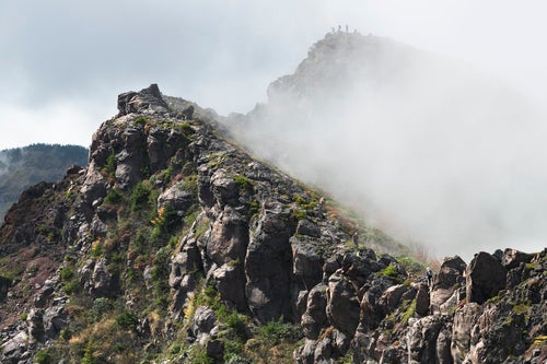 ガスに包まれた蛇骨山の稜線を歩く登山者（浅間山）の写真