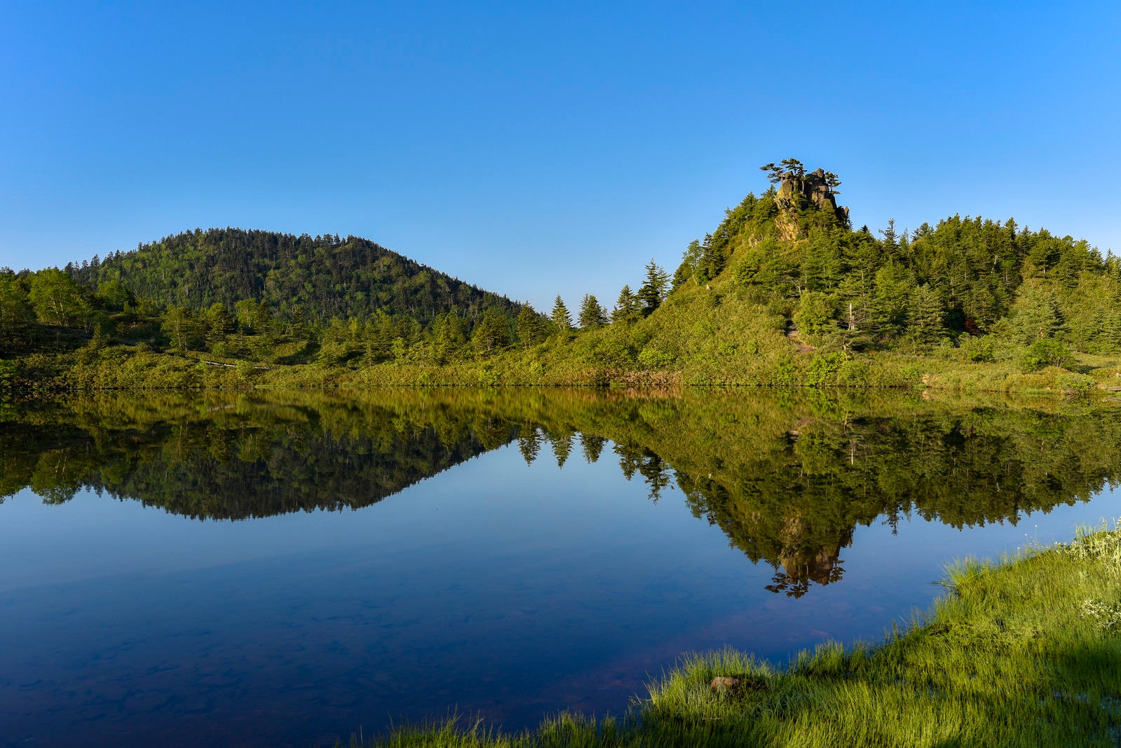 「湖面に反射する弓池の景色（草津白根山）」の写真