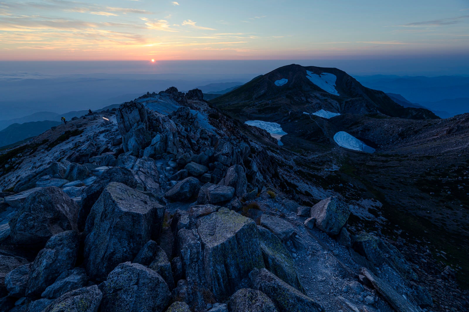 「御前峰の荒々しく積み重なった岩と沈みゆく太陽（白山）」の写真
