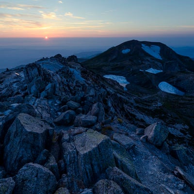 御前峰の荒々しく積み重なった岩と沈みゆく太陽（白山）の写真