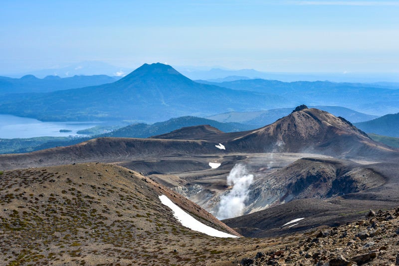噴煙拭きあがる火山性の大地が広がる雌阿寒岳（めあかんだけ）の写真