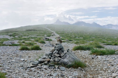 双六岳山頂のケルンとガスの向こうの槍ヶ岳（水晶岳）の写真
