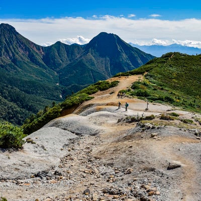 赤岳を見ながら硫黄岳を登る登山者たちの写真