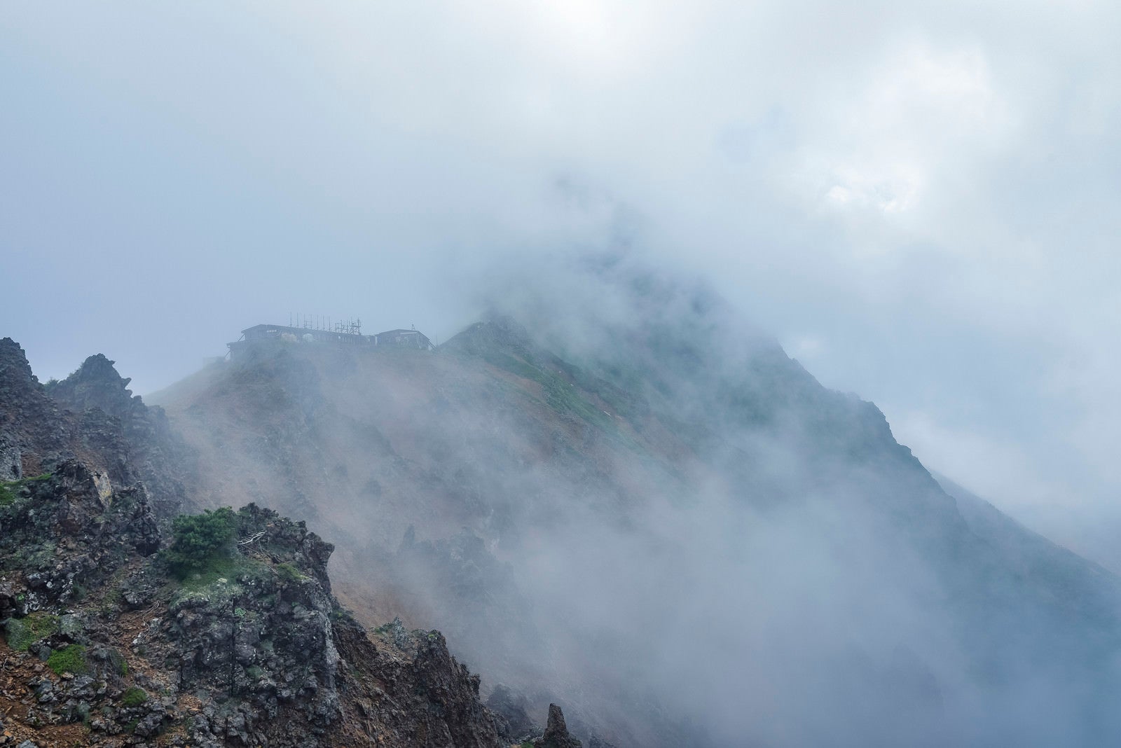 「雲の中にうっすらと姿を見せる赤岳と小屋」の写真