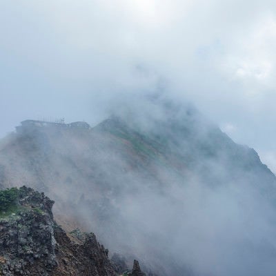 雲の中にうっすらと姿を見せる赤岳と小屋の写真