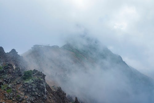 雲の中にうっすらと姿を見せる赤岳と小屋の写真