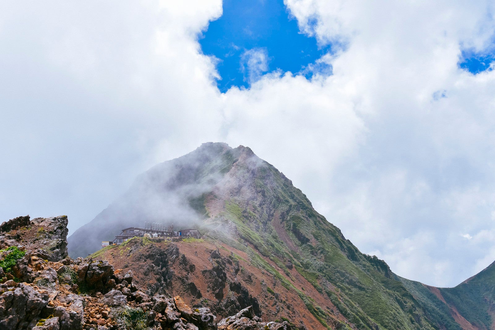 「青空の下に顔を出した赤岳山頂（地蔵尾根から）」の写真