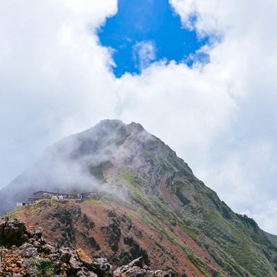 青空の下に顔を出した赤岳山頂（地蔵尾根から）の写真