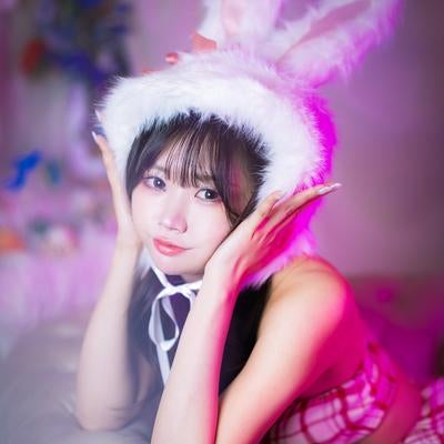 ピンク照明の中でにっこり笑うバニートラップ姿の女性の写真