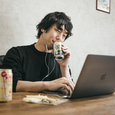 缶チューハイを飲みながら在宅勤務しているエンジニアの写真