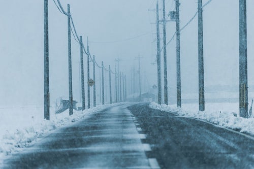 雪国の降雪とどこまでも続く電柱の写真