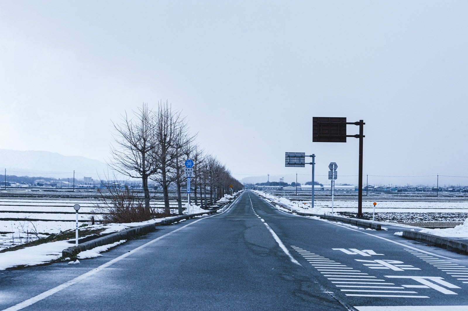 「どこまでも続く車道と冬景色」の写真