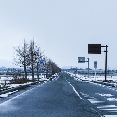 どこまでも続く車道と冬景色の写真