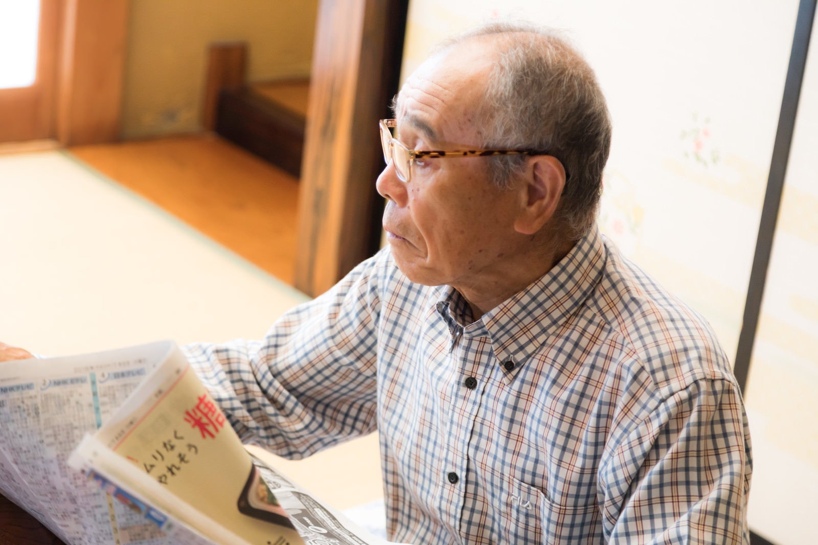 「居間で新聞を読むお爺さん」の写真［モデル：まーちゃん］