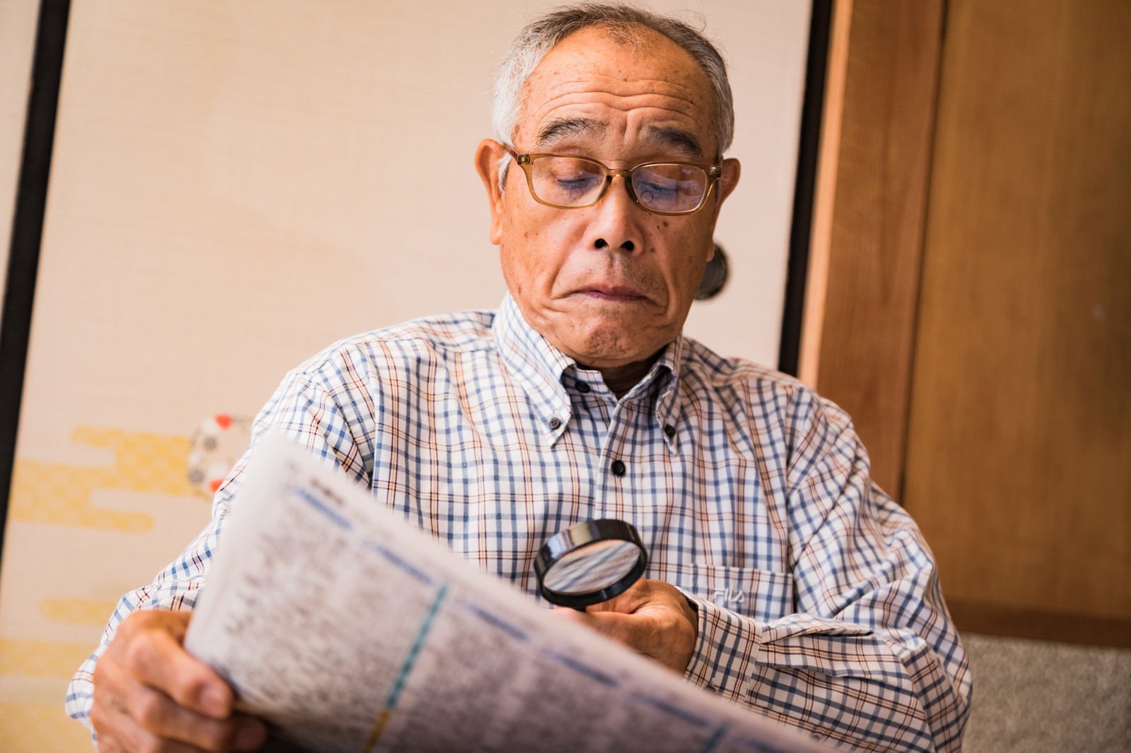 「拡大鏡で新聞を読むおじいさん」の写真［モデル：まーちゃん］