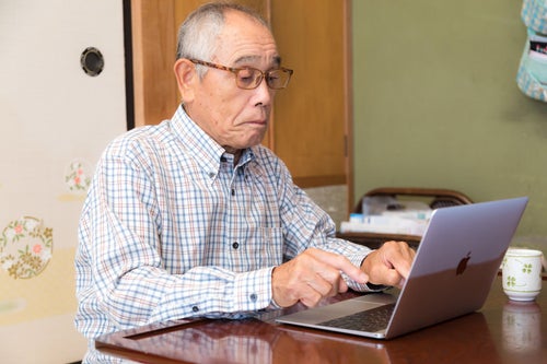 MacBook でブログを書くお爺さんの様子の写真