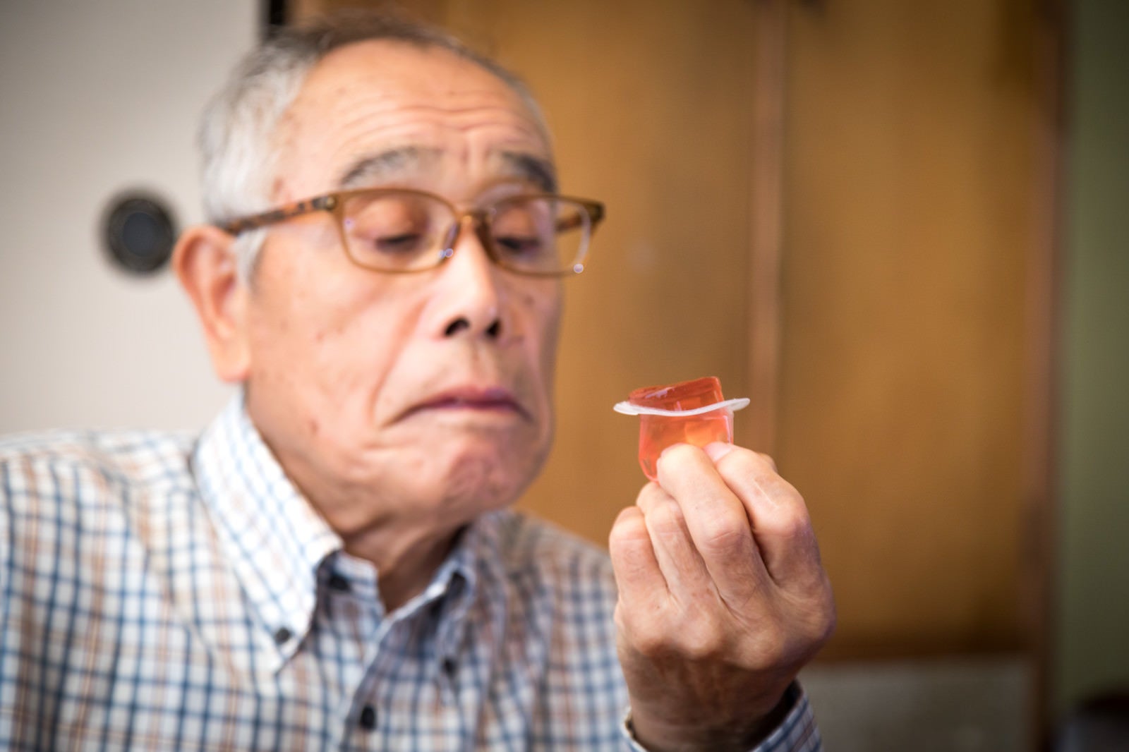 「祖父がこんにゃくゼリーを食べようとしています」の写真［モデル：まーちゃん］