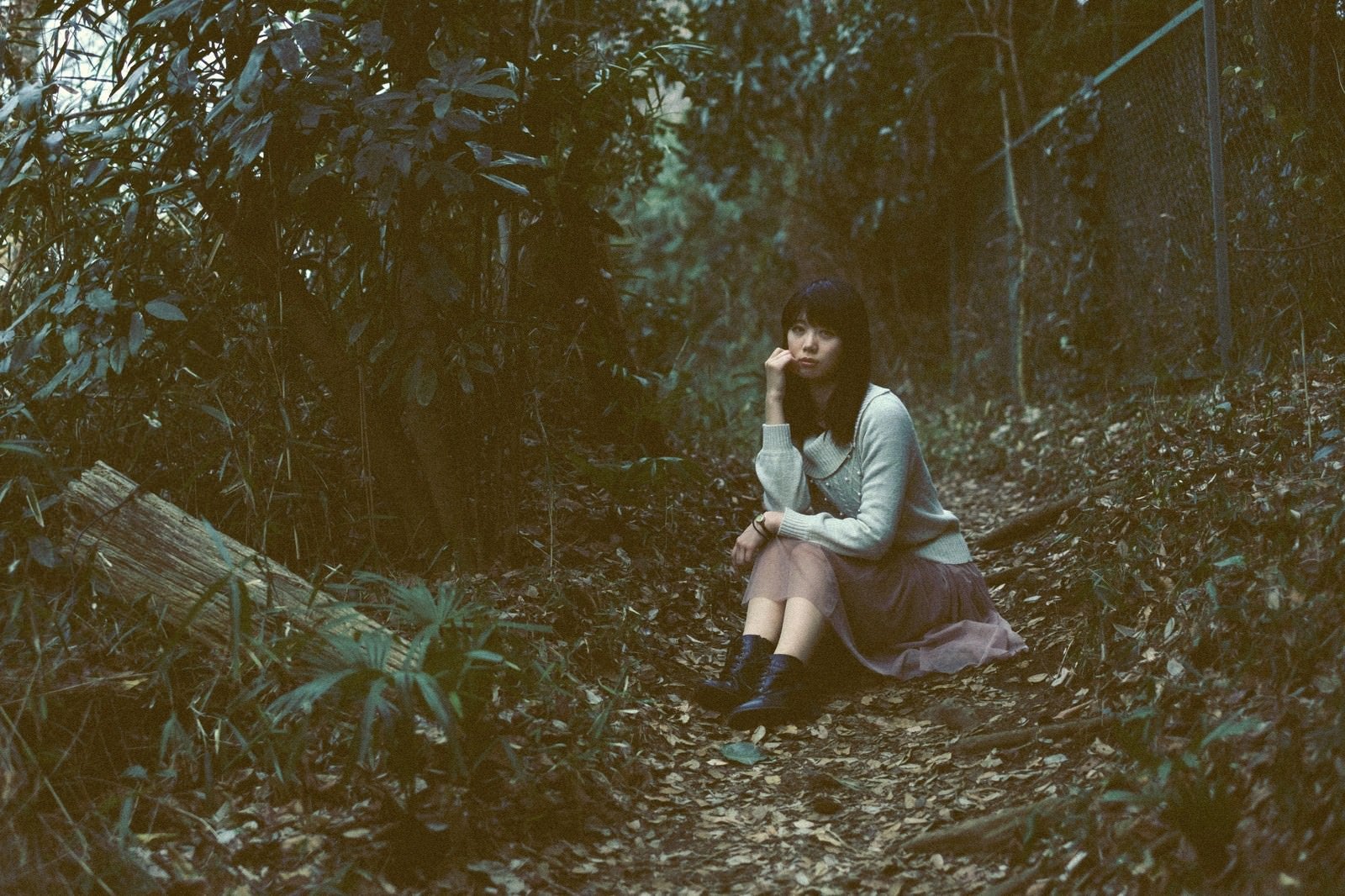 「森のなかで座り込む女性」の写真［モデル：モデルリリース］