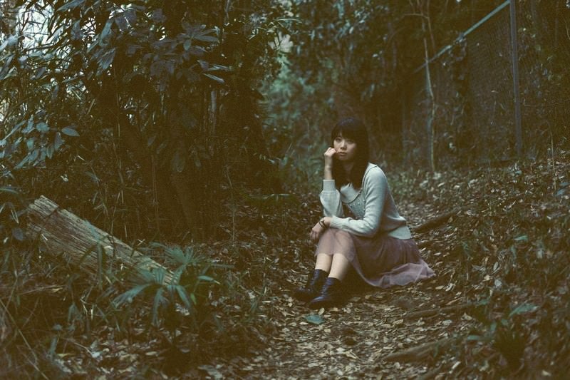 森のなかで座り込む女性の写真