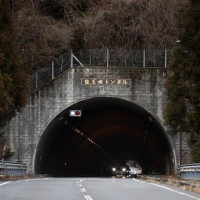 山道を走る車が通過する龍王峡トンネルの昼間風景の写真