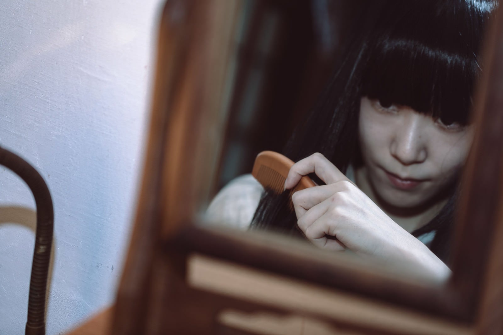 「鏡を見ながら櫛を通す女性」の写真［モデル：緋真煉］