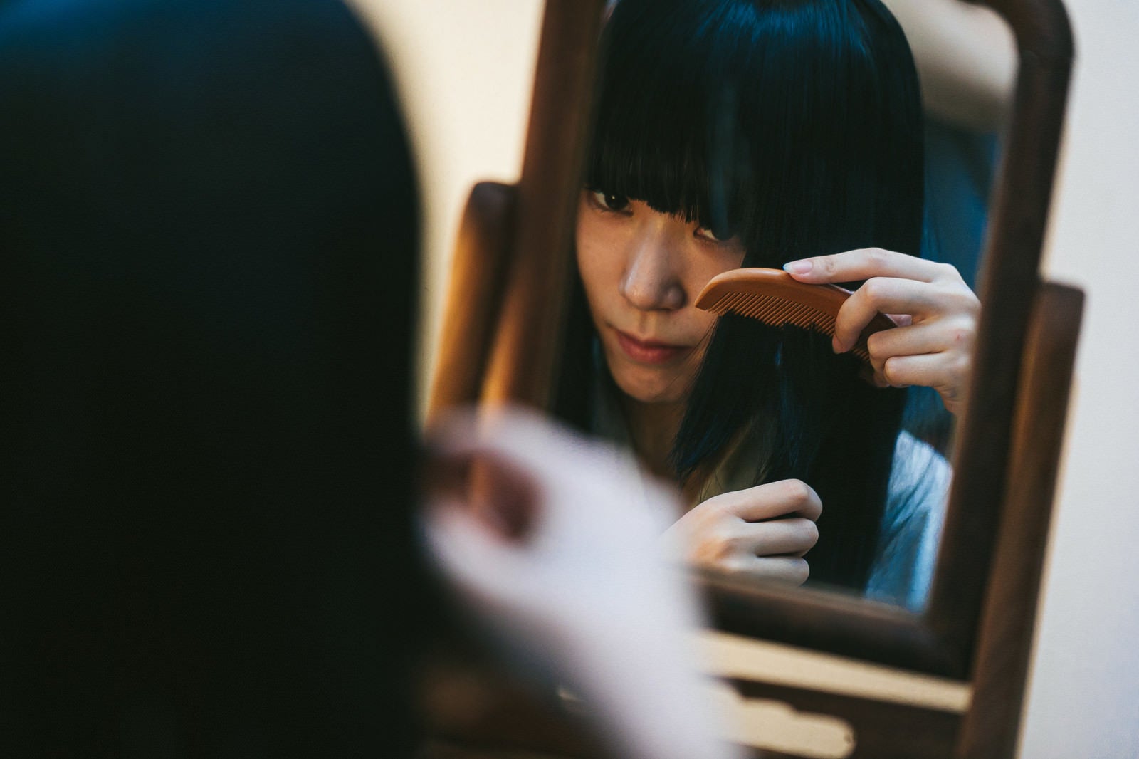 「鏡を使って髪をとかす日本女性」の写真［モデル：緋真煉］